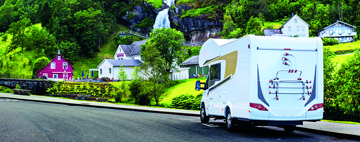 rin mit REMISmobil-Zubehör ausgestatteter Wohnwagen auf einer idyllischen Landstrecke